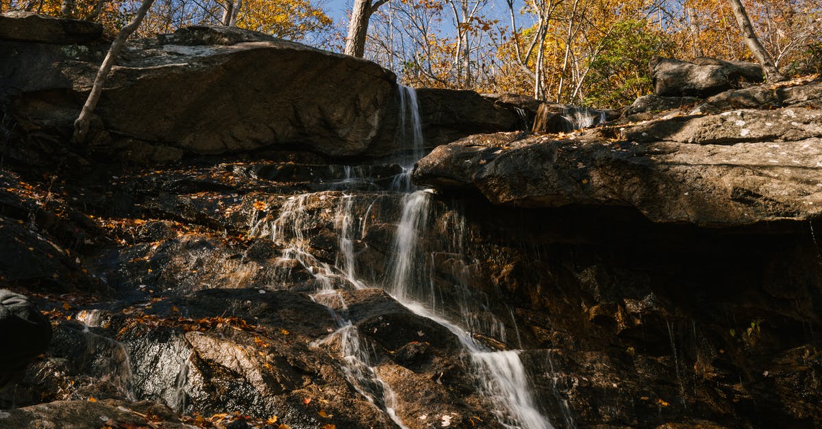 In Overwatch coop can we make heavy assault fall off cliff? - Fast waterfall flowing through heavy rocks in autumn forest under bright clear blue sky