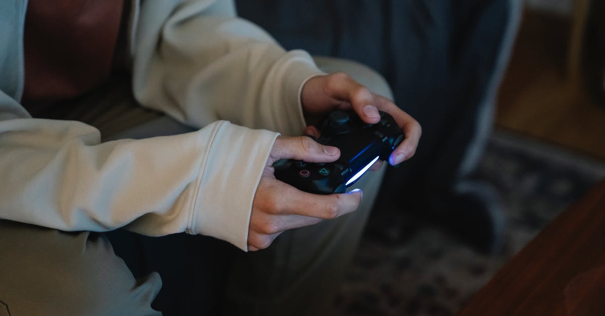 Invert gamepad button to avoid RSI - Crop unrecognizable man with joystick playing video game while sitting on couch in house room