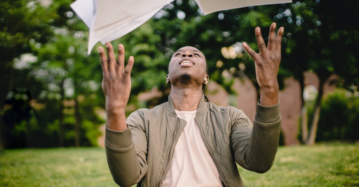 Is it possible to get a Free Magic Shield? - Content black remote worker throwing work papers in air happy to get rid of boring paperwork while sitting in green park with laptop