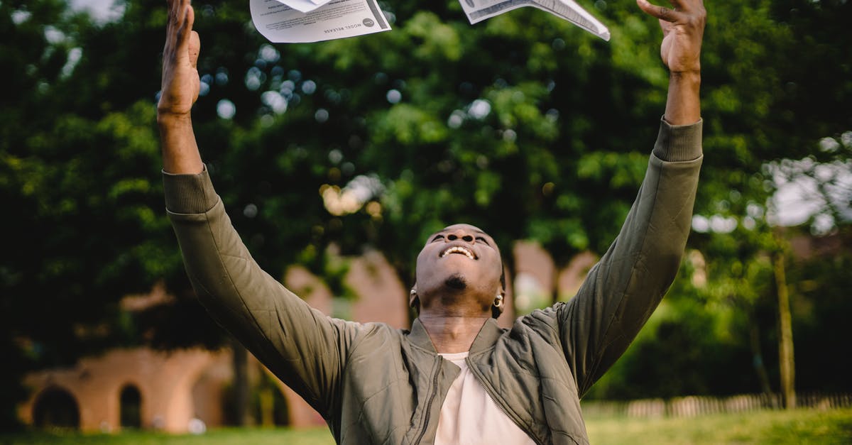 Is it possible to get a Free Magic Shield? - Happy African American remote worker tossing papers in air happy to get rid of boring paperwork while sitting in green park