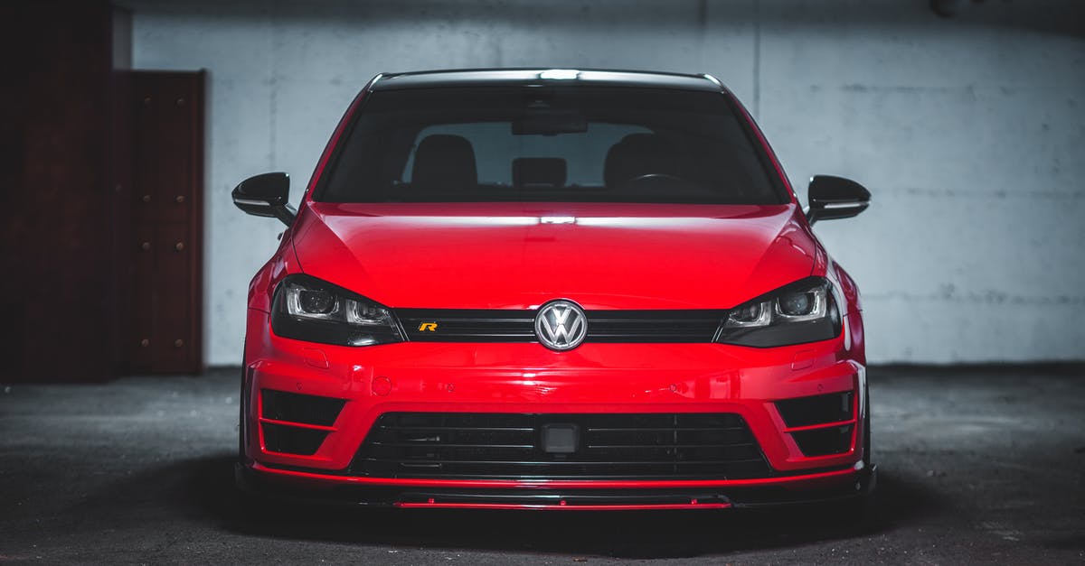 Is it possible to place an outgoing underground belt first? - Modern red automobile with shiny surface parked on asphalt lot of dark underground parking