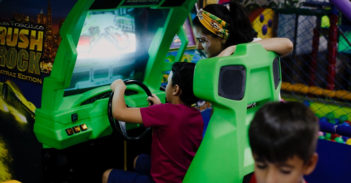 Is it possible to play car racing games with a joystick? - Anonymous boy playing car racing simulator near mother and sibling