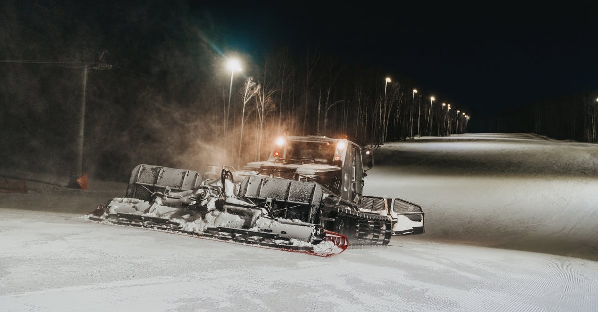 Is it possible to remove viewscreen weather effects? - Snowcat removing snow from bumpy road with shadows against streetlamps under dark sky in twilight