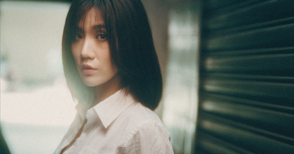 Is it possible to reset your character and town name? - Young ethnic female in white blouse looking at camera while resting on city street