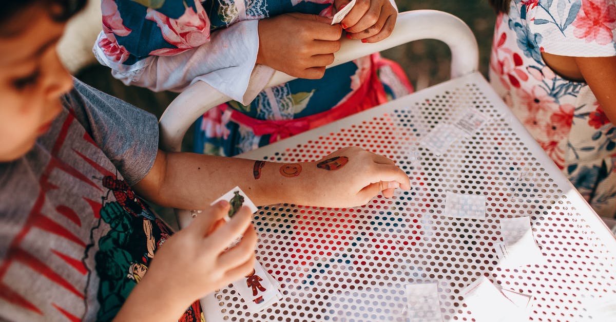 Is it possible to turn off shared games from your friend? - From above of anonymous kids in casual clothes standing near white table and playing with small cards in sunny day