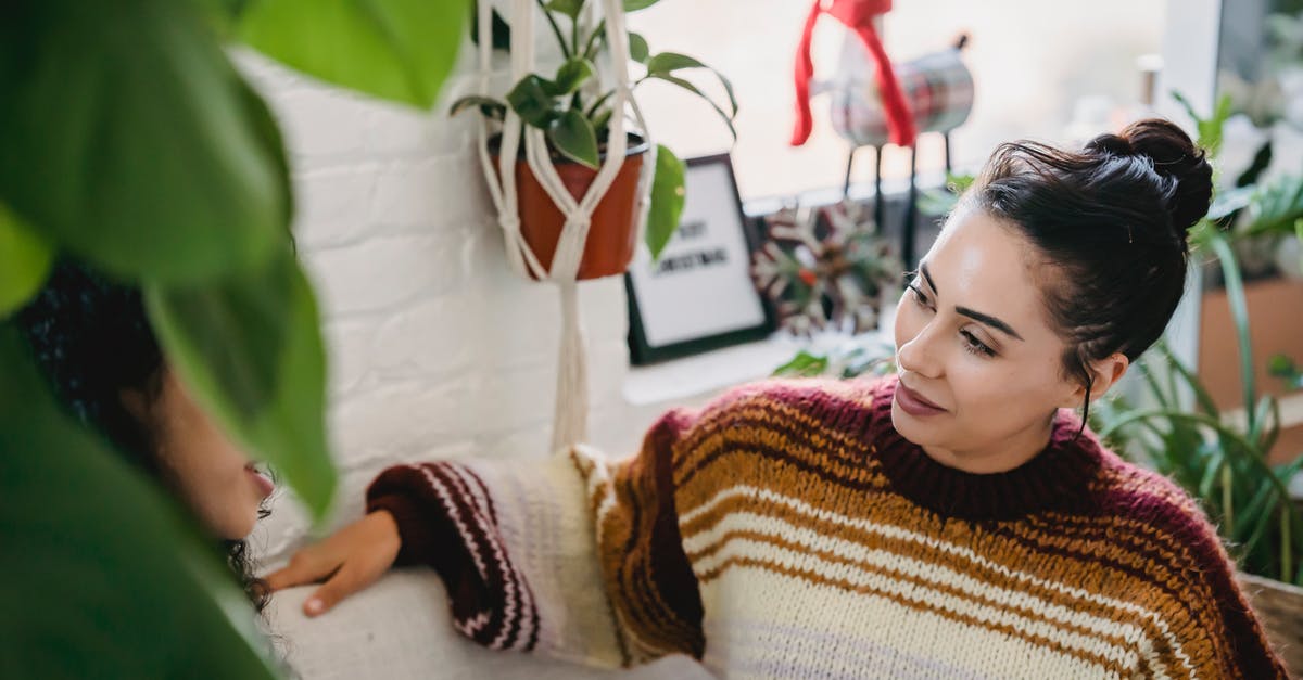 Is it possible to turn off shared games from your friend? - From above of young female in casual clothes sitting on comfortable couch and talking to friend while resting in cozy room