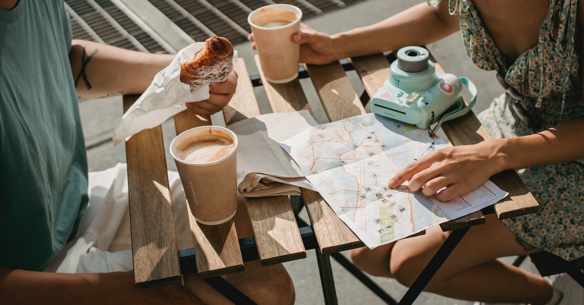 Is map refreshing instantly after destroying an altar? - From above of crop anonymous couple searching route in map while having coffee and croissant