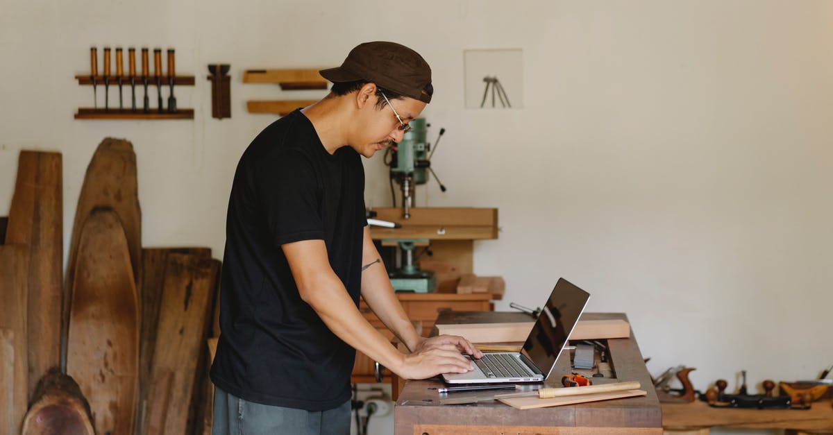 Is there a connection between The Master and MODUS? - Concentrated ethnic guy browsing laptop in woodworker workshop