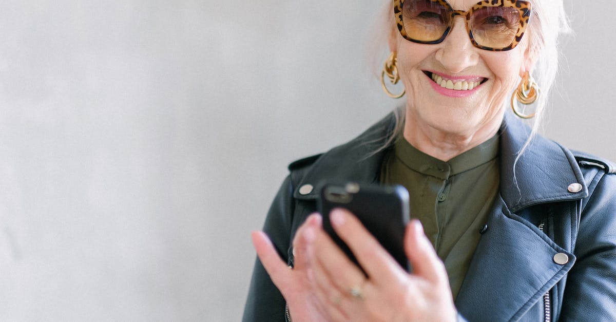 Is there a “special edition” version of The Elder Scrolls Online? - Crop happy senior female in stylish jacket touching screen of mobile phone while smiling and looking at camera