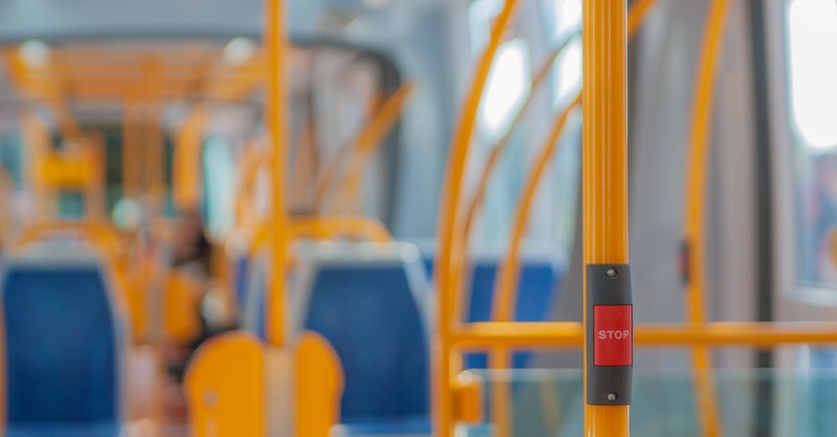 Is there a way to change displayed buttons? - Red stop button on yellow handrail in modern empty public bus during daytime