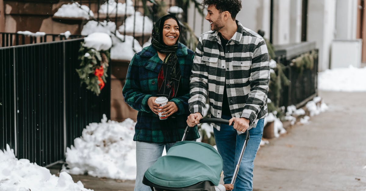 Is there a way to keep the BGM going while paused? - Happy ethnic couple walking with stroller on street in residential city district