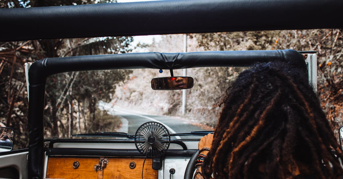 Is there a way to rearrange your inventory? - Back view of unrecognizable traveler with stylish dreadlocks spinning steering wheel while driving car and reflecting in small mirror