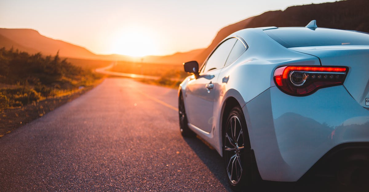 Is there a way to unlock higher graphics settings? - Modern white automobile riding on empty roadway among green plants at sundown time with sun setting on horizon in summer time