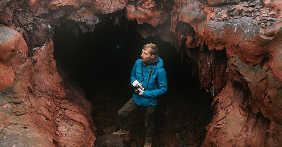 Is there actually a cave entrance on every screen? - Man Standing in the Entrance to a Stalactite Cave