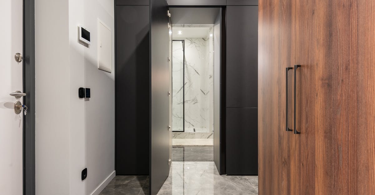 Is there actually a cave entrance on every screen? - Corridor with tiled marble floor and closet against doors in contemporary house with shiny lights