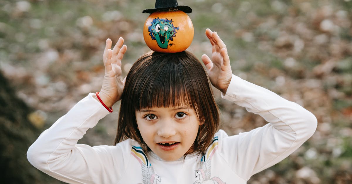 Is there party level balancing? - High angle of happy child in casual clothes standing in park with pumpkin on head and looking at camera