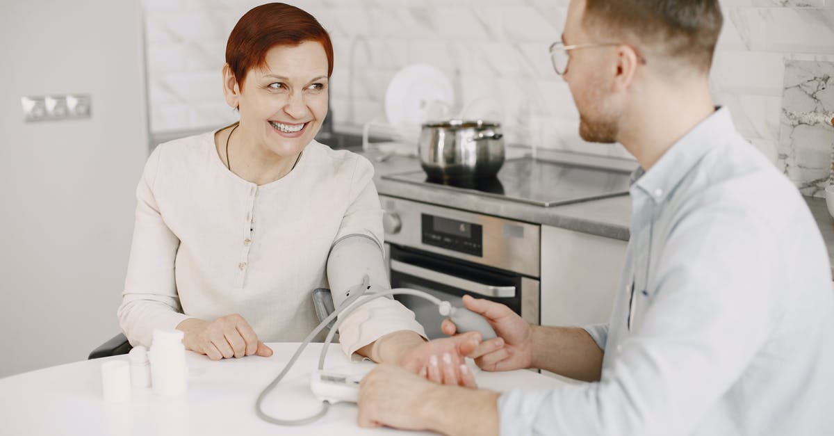 Is this supposed to be blood? - A Man Sitting at a Table Checking a Woman's Blood Pressure