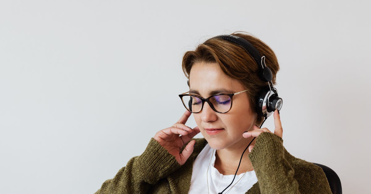 JAMMA Arcade: How to properly wire audio - Content glad female wearing eyeglasses and headphones listening to good music and touching headset while sitting with eyes closed against white wall