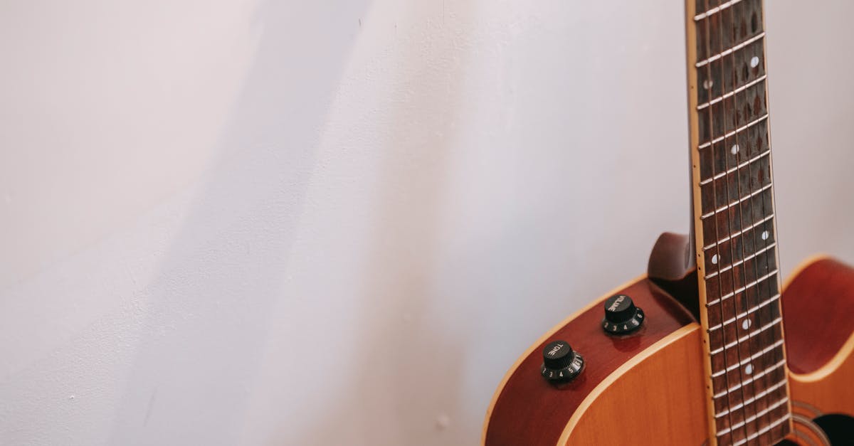 Key Fragment chance reset rate - Detail of guitar neck with volume and tone knobs on body of brown musical instrument placed near white wall with shadow