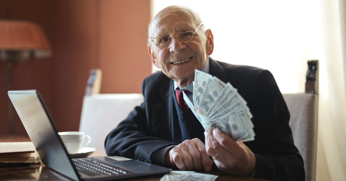 Lag on old PC games until a gamepad is connected - Happy senior businessman holding money in hand while working on laptop at table