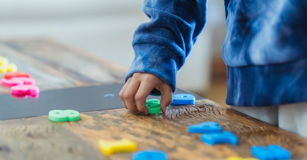 Level 1, Think Different missing number - Crop anonymous ethnic boy taking plastic number from wooden table while learning math