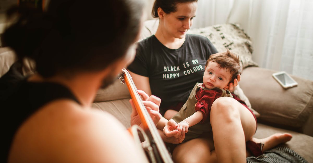 Love Live without the music - Anonymous father playing guitar on couch for baby and wife