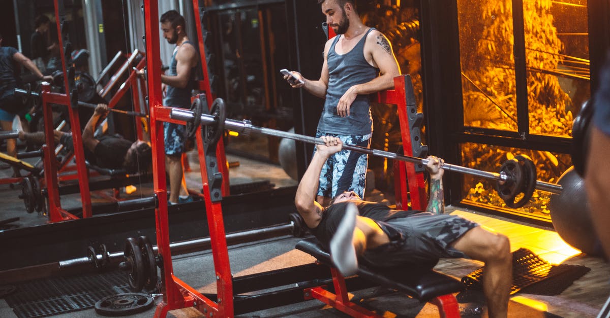 Machines keep using power - Sporty fitness trainer and man lifting barbell