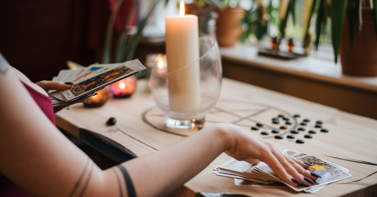 MineBlocks Enchantment? - Crop unrecognizable fortune teller predicting fate with tarot cards near shiny candle at home