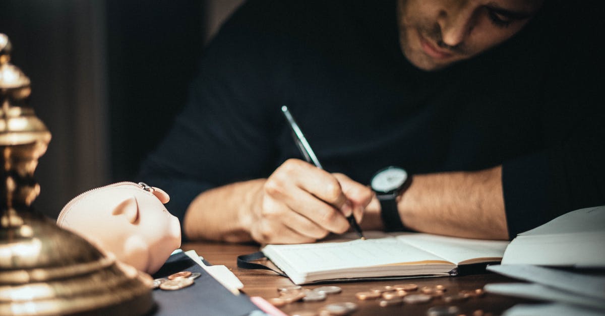 Minecraft Account - Crop elegant man taking notes in journal while working at desk with coins and piggybank in lamplight