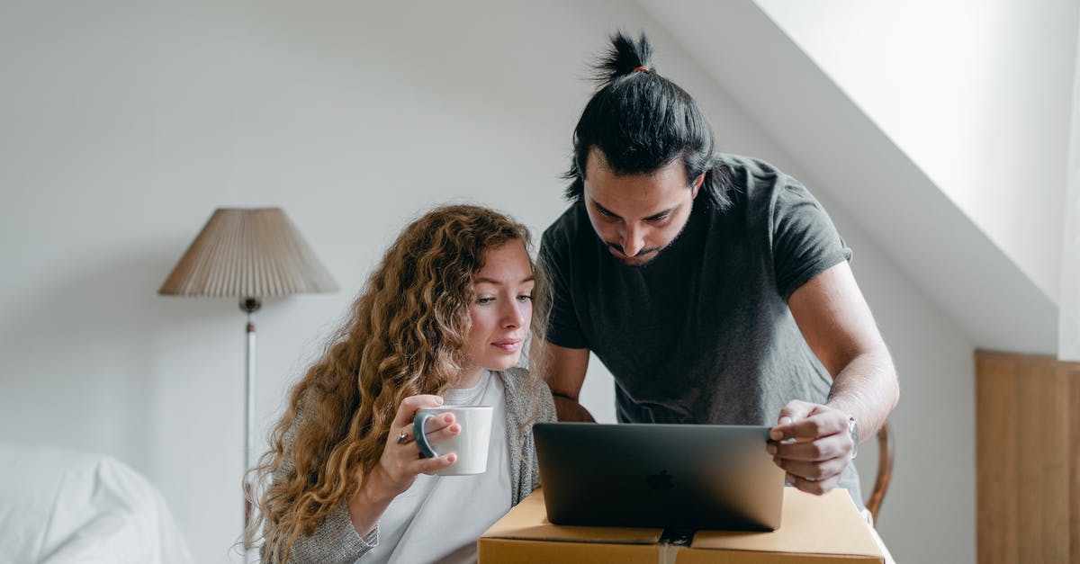 Minecraft glitching out on PC - Concentrated young couple in casual outfit browsing netbook and packing stuff into carton boxes and suitcases to move out