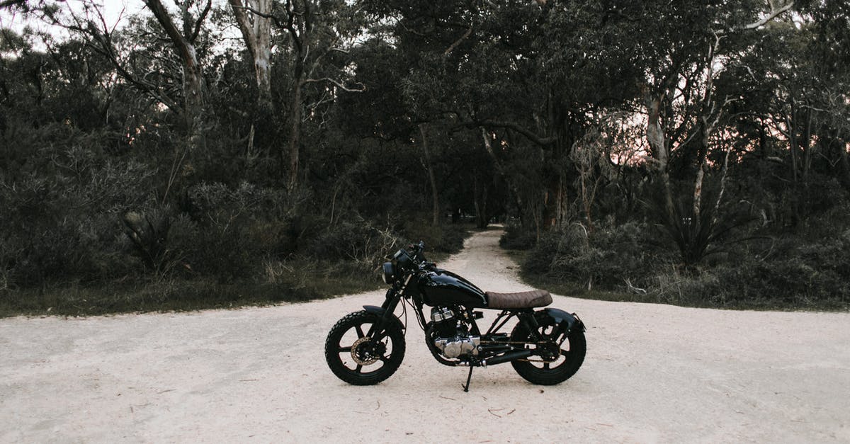 Motor skill: Let speed come naturally? - Black metal motorbike parked on sandy road near trees and green grass in daytime