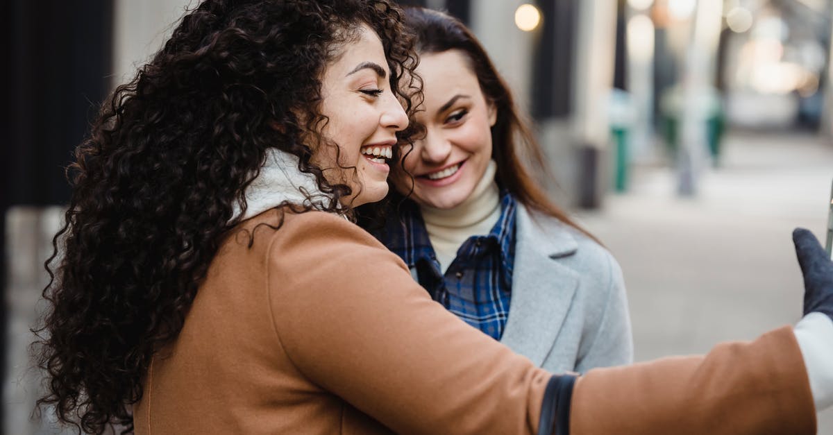 Mount and Blade Warband - How to capture a friendly town? - Side view of smiling multiracial female friends in warm clothes taking self portrait while standing on sidewalk on street against blurred background