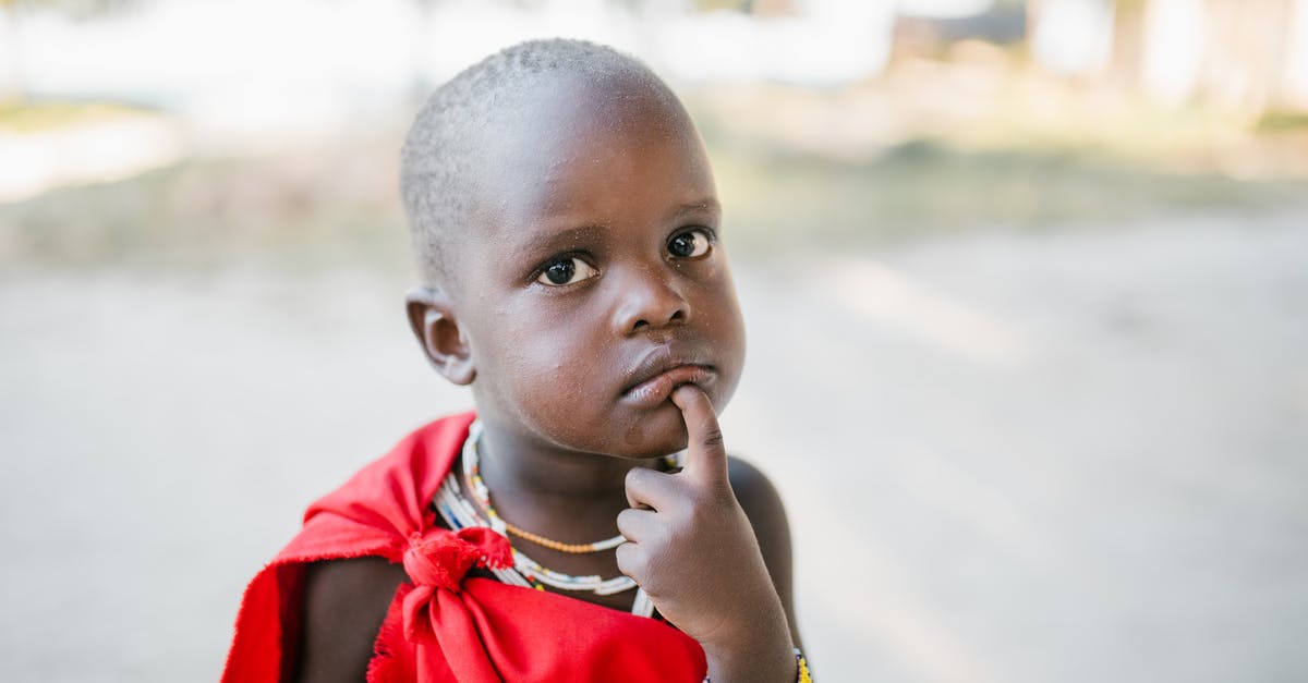 My Minecraft Native Launcher Won't Download - Curious black child in red cover touching chin and looking at camera with interest while standing on sunny street