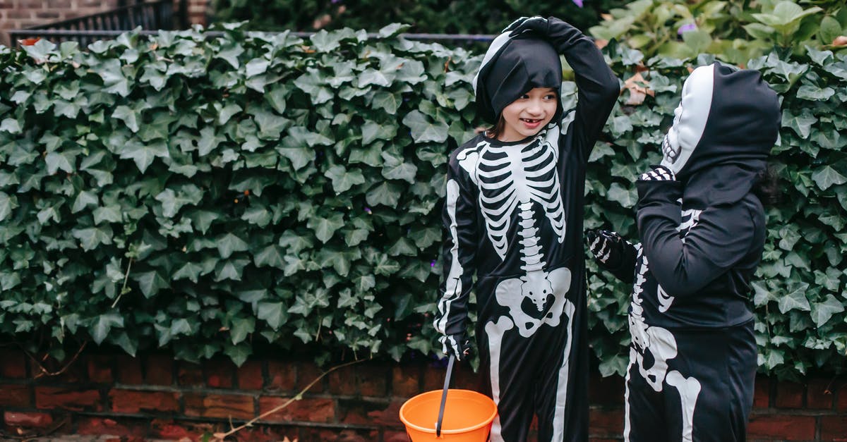 Natural skeleton horses? - Little kids in Halloween skeleton jumpsuits with orange bucket in autumn garden