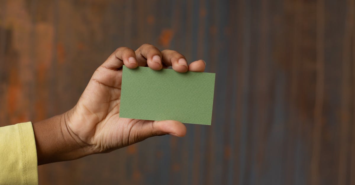 Nothing shows on part of scanner - Unrecognizable African American person showing green mock up business card in hand while standing near wooden wall in modern studio