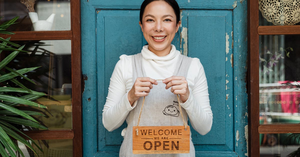 Only show region title for players entering/exiting the area in Bedrock edition? - Cheerful ethnic female cafeteria owner in apron demonstrating cardboard signboard while standing near blue shabby door and windows after starting own business and looking at camera