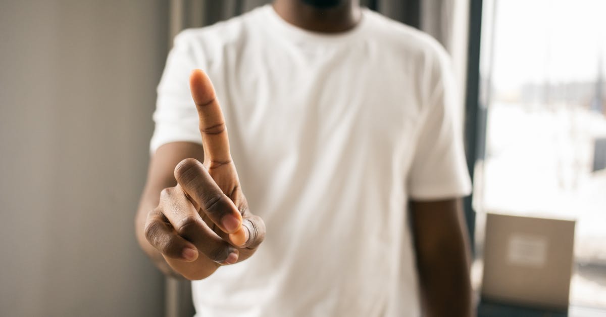 Pointers to closest portals don't show up - Crop anonymous African American male in white t shirt showing stop gesture with index finger pointing up in light room on blurred background