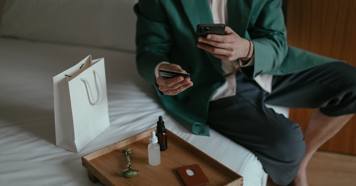 Pokémon bank and home - Anonymous man using smartphone while placing order with credit card sitting near cosmetic products