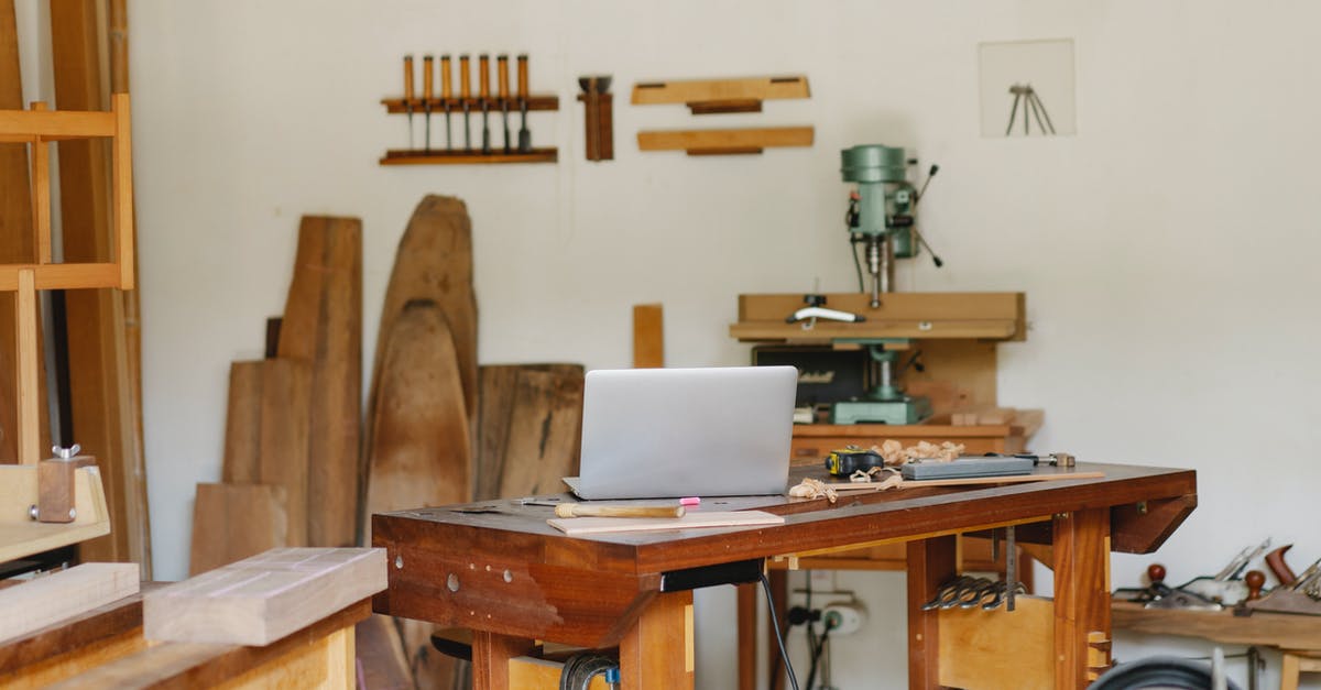 Portable DOSBox machine - Workroom interior with assorted wooden pieces near wall and drill press against netbook in daylight