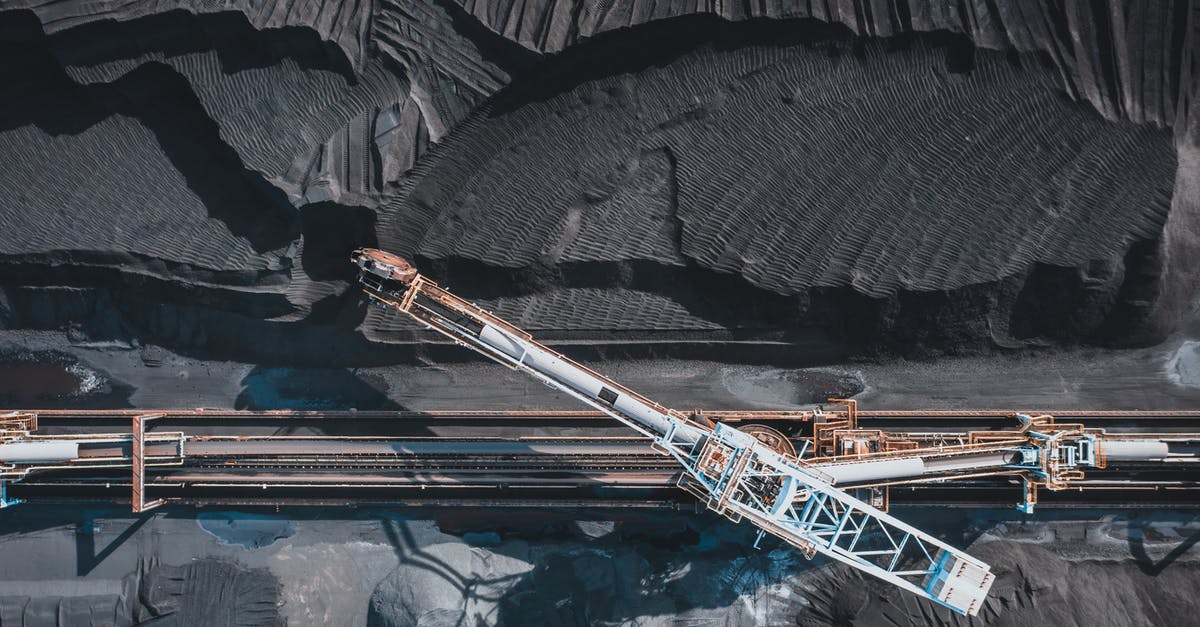 Power golden rails from minecart(placing rails in large scale) - Top view of modern industrial machinery working with black natural coal in daylight