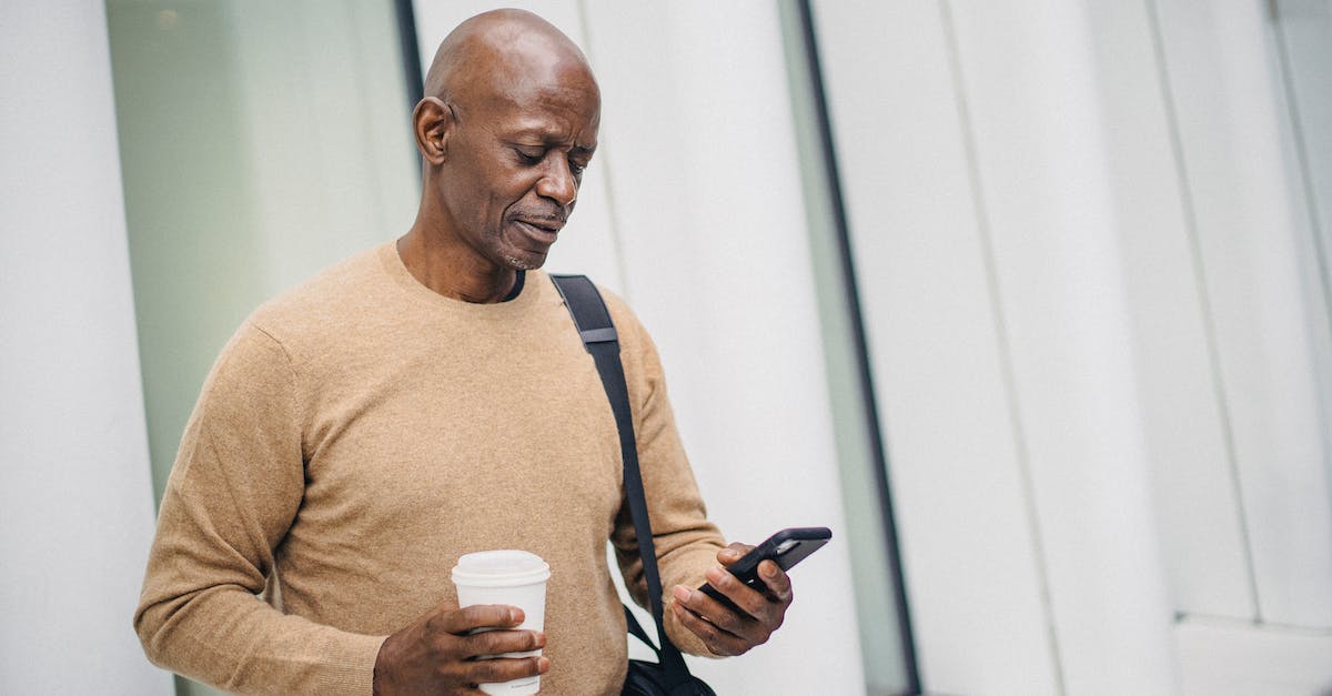 Premature vs Mature town hall - Serious black man with smartphone and takeaway coffee