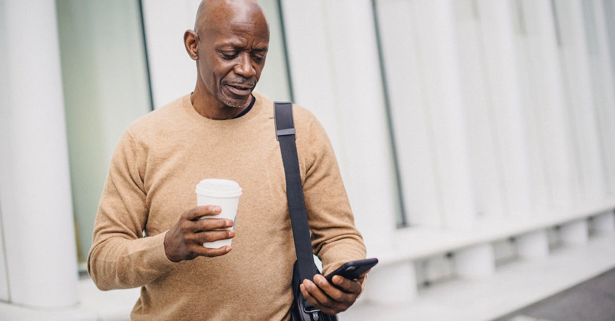 Premature vs Mature town hall - Content ethnic businessman texting on phone in city