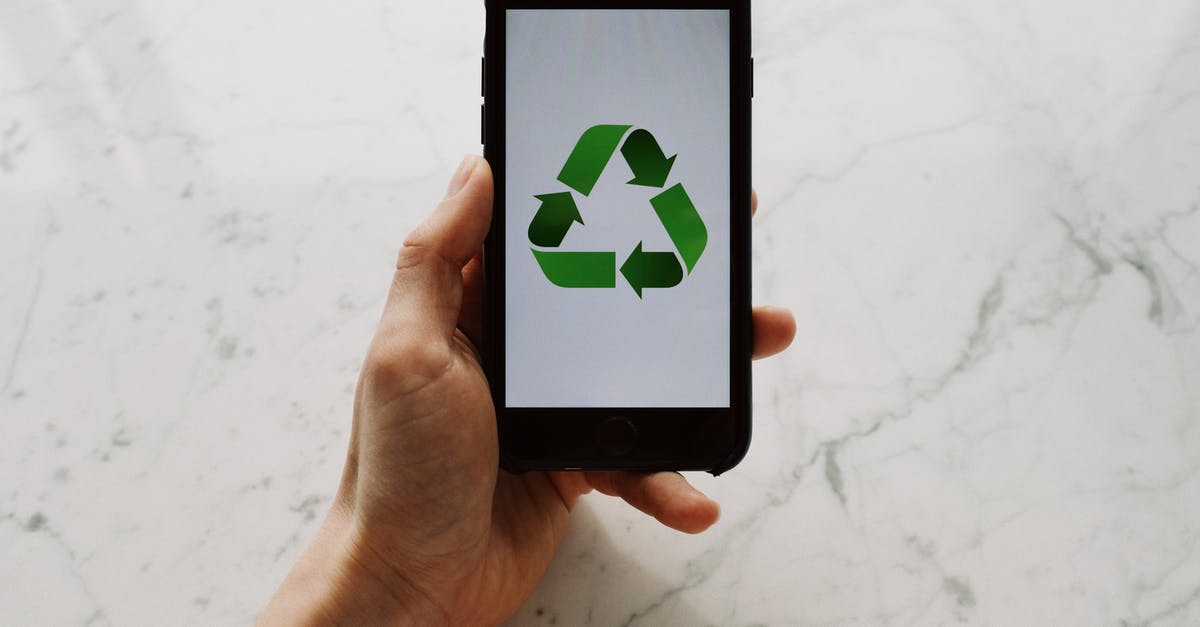 Prevent AI from using Venice - From above view of faceless person holding mobile phone with white screen and green recycle logo above marble surface