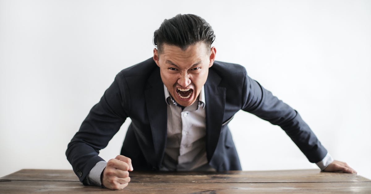 Problems with the Draug boss fight - Expressive angry businessman in formal suit looking at camera and screaming with madness while hitting desk with fist