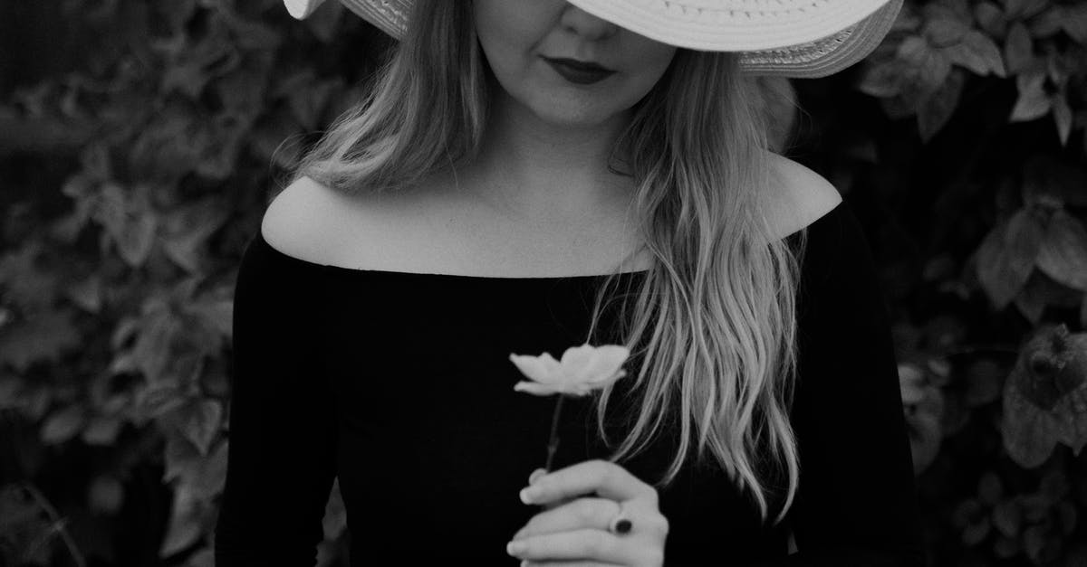 Ring of hircine and saviors hide - Black and white of crop anonymous gentle female in hat with blossoming flower against shrubs