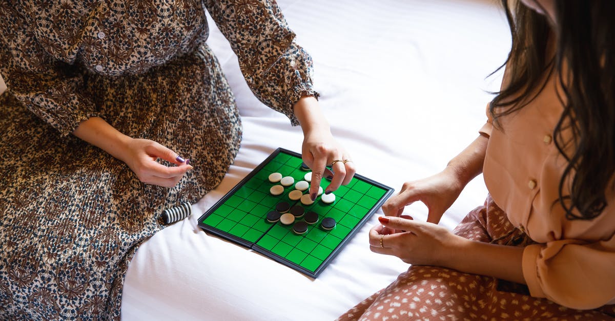 Ripping PS2 game disks - Crop unrecognizable women playing reversi game on bed