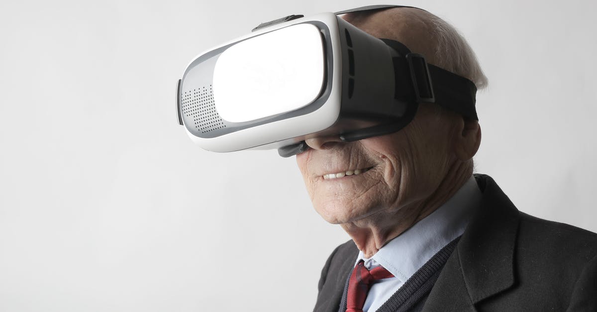 Shaking a virtual wiimote - Smiling elderly gentleman wearing classy suit experiencing virtual reality while using modern headset on white background