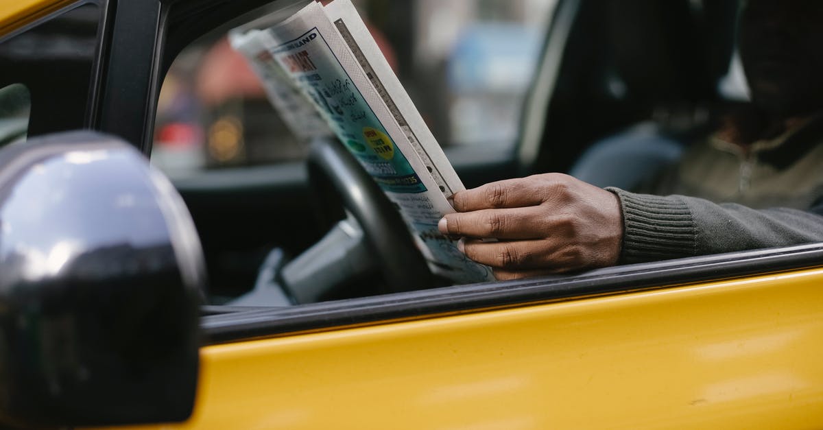 Should I wait until post-game to read Secret Reports? - Side view of crop anonymous ethnc male driver reading information in newspaper article while waiting for client