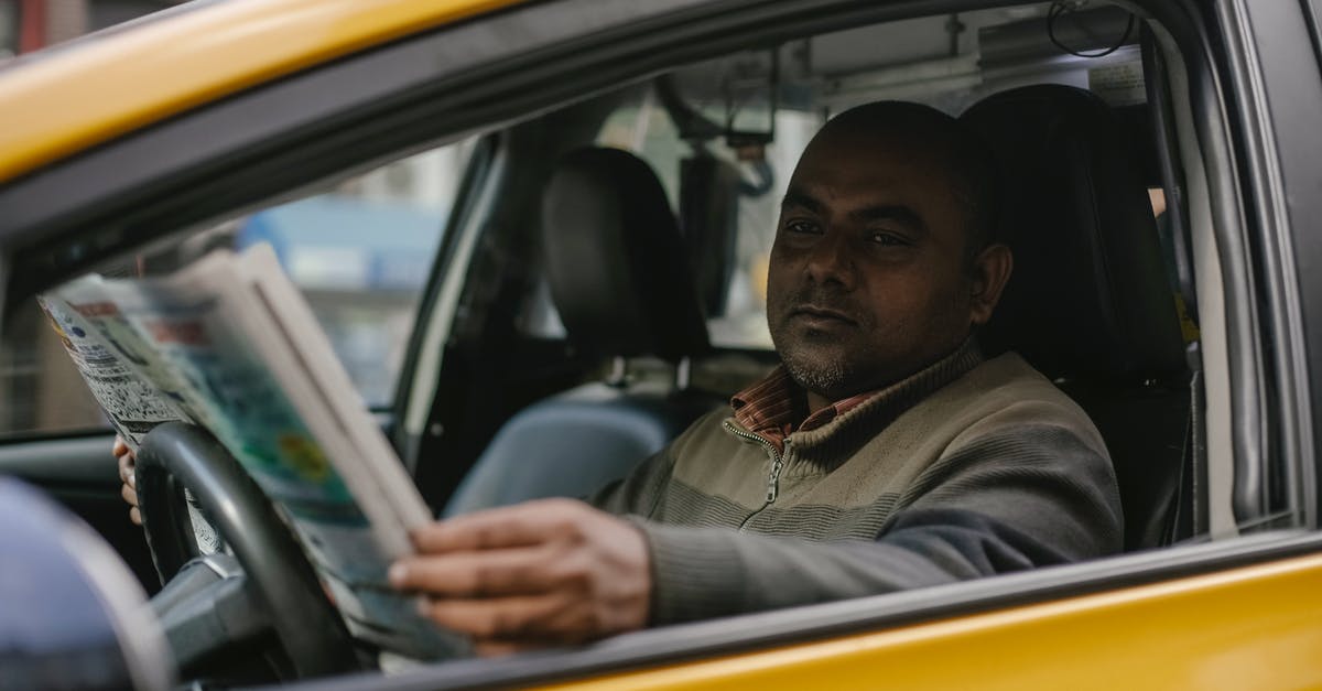 Should I wait until post-game to read Secret Reports? - Concentrated ethnic male driver sitting at steering wheel and reading magazine while waiting for client