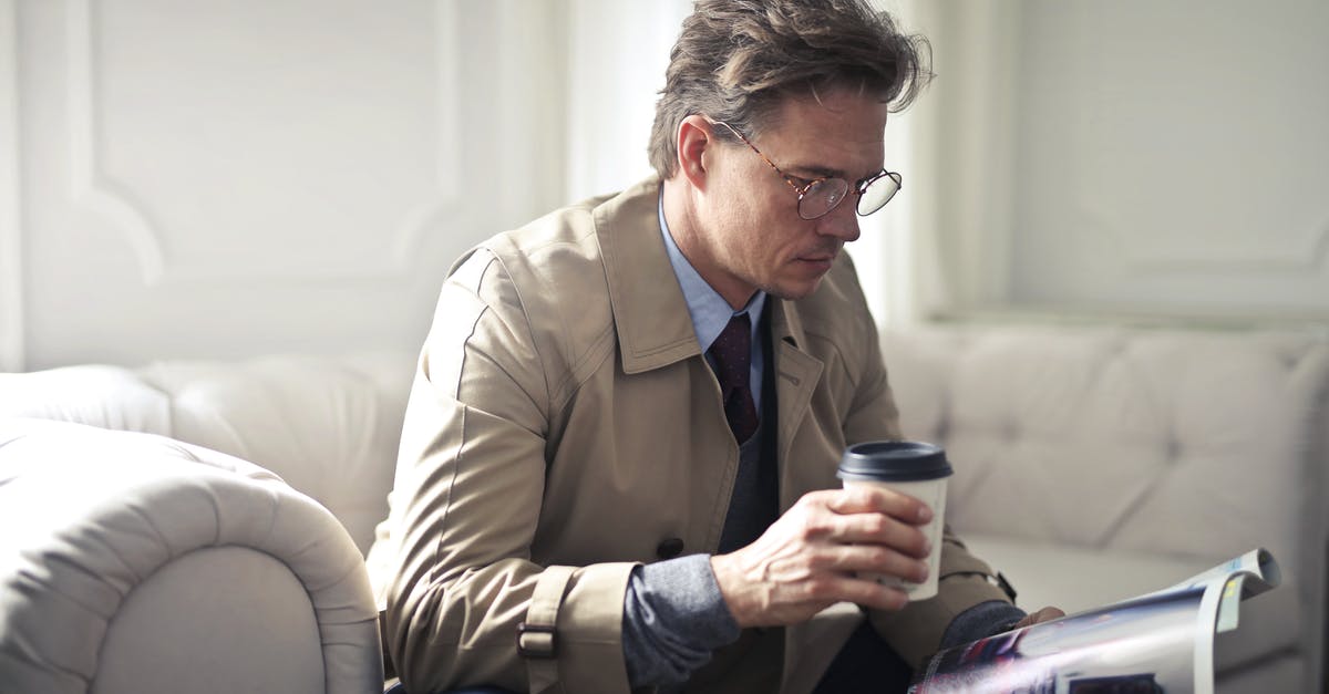 Should I wait until post-game to read Secret Reports? - Concentrated businessman with takeaway coffee reading magazine in living room